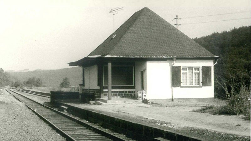alte schwarz-weiß Fotografie, die die Schienenführung und das Bahnhofsgebäude von Freisen aus dem Jahr 1978 zeigt. 
