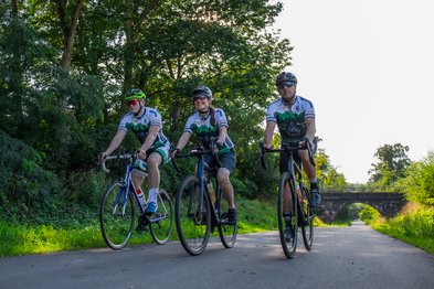 Drei sportliche Radfahrer fahren mit Rennrädern auf dem Bahnradweg