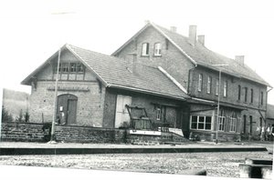 schwarz-weiß Aufnahme des Bahnhofgebäudes in Nonnweiler aus dem Jahr 1978. Es besteht aus 2 aneinander gebauten Häuschen, das linke ist etwas kleiner und niedriger, der rechte etwas höher und größer.
